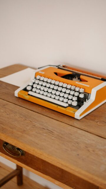 Vintage Orange Typewriter on Wooden Desk Aesthetic Phone Wallpaper