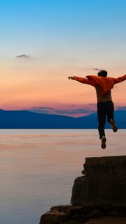 Man Jumping into Lake at Sunset Adventure Phone Wallpaper