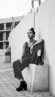 Stylish Woman in Polka Dot Jumpsuit Posing by Concrete Wall Wallpaper