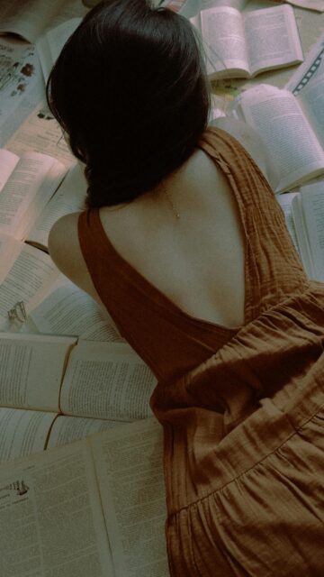 Aesthetic Woman Lying on Books Moody Dark Academia Phone Wallpaper