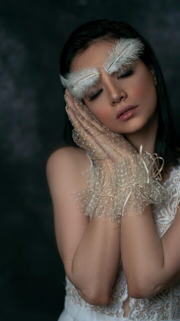 Ethereal Woman with Feather Eyebrows and Lace Gloves Mobile Wallpaper