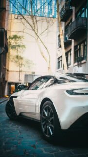 Sleek White Luxury Sports Car in City Alleyway Mobile Wallpaper