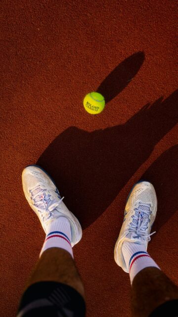 First-Person Perspective Tennis Court View with Roland Garros Ball Wallpaper