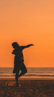 Silhouette of a Man Performing an Athletic Pose at Sunset Wallpaper