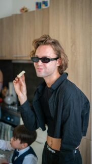 Stylish Man Eating Snack in Modern Kitchen Casual Aesthetic Wallpaper