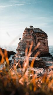 Stunning Man Standing on a Massive Coastal Rock Formation Phone Wallpaper