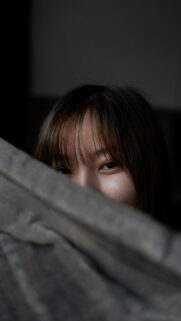 Mysterious Asian Girl Peeking Behind Shadowy Wall 4K Phone Wallpaper