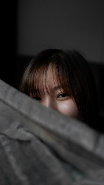 Mysterious Asian Girl Peeking Behind Shadowy Wall 4K Phone Wallpaper