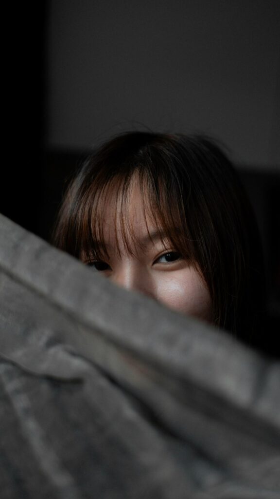 Mysterious Asian Girl Peeking Behind Shadowy Wall 4K Phone Wallpaper