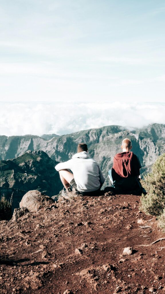 Two Friends Sitting on Mountain Peak Above Clouds Mobile Wallpaper