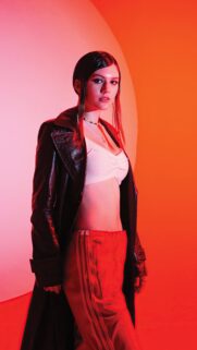 Stylish Fashion Model in Leather Coat with Vibrant Neon Lighting Background