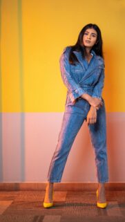 Stunning Fashion Model in Denim Jumpsuit Against Vibrant Yellow Background