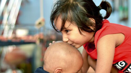 Heartwarming Older Sister Kissing Baby Brother 4K Desktop Wallpaper