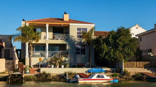 Luxury Waterfront Home with Private Boat at Sunset Desktop Wallpaper