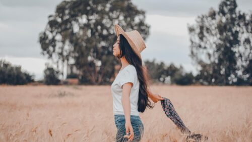 Woman Walking in Golden Wheat Field at Sunset Desktop Wallpaper