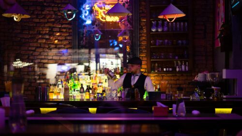 Professional Bartender Crafting Drinks in Neon Lit Bar 4K Wallpaper