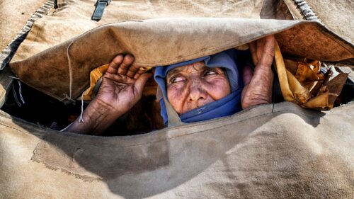 Elderly Woman Peering Through Canvas Tent Opening 4K Desktop Wallpaper