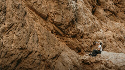 Woman Drinking Water on Desert Canyon Rock Face 4K Wallpaper