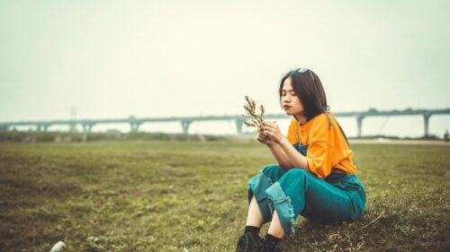 Young Woman Sitting in Meadow Holding Dried Flowers Desktop Wallpaper