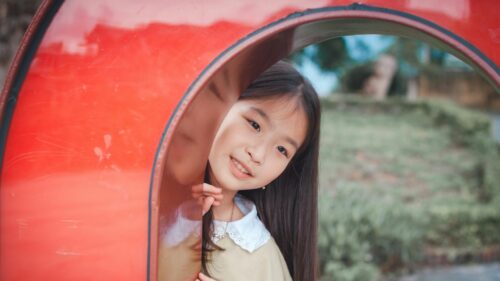 Cute Asian Girl Looking Through Red Play Tunnel Desktop Wallpaper