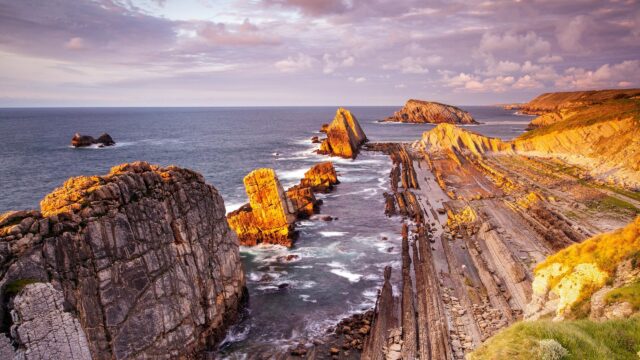 Breathtaking Golden Hour Seascape with Jagged Rock Formations 4K Wallpaper