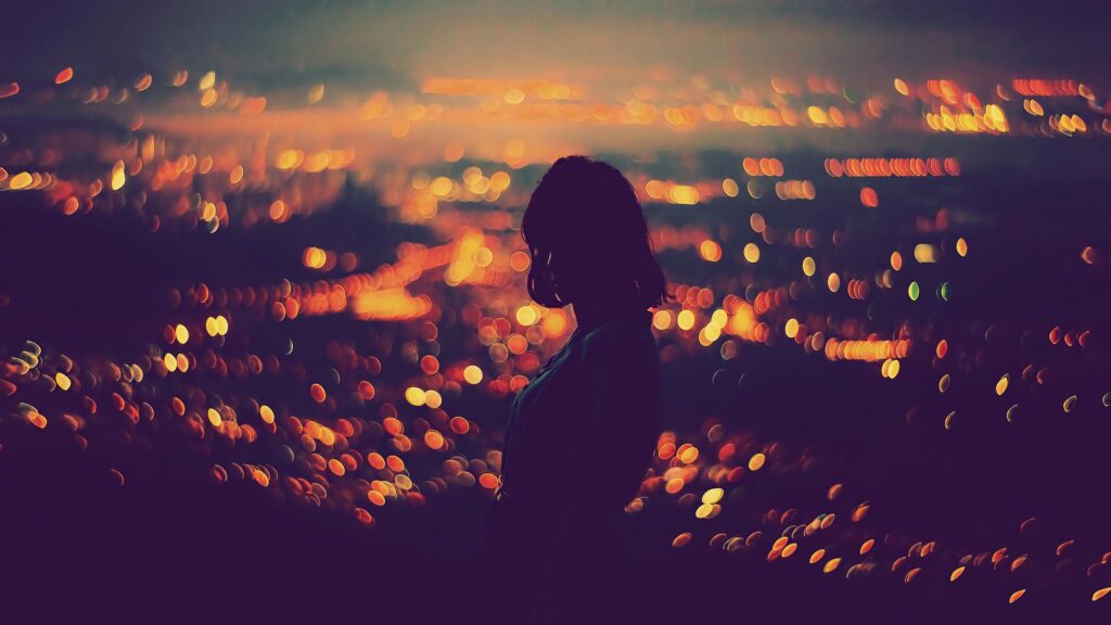 Silhouette of a Woman Against Ethereal City Lights 4K Desktop Wallpaper