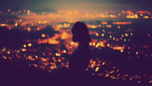 Silhouette of a Woman Against Ethereal City Lights 4K Desktop Wallpaper