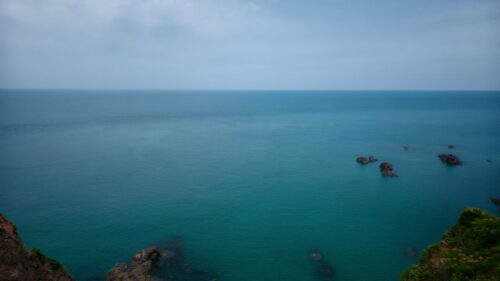 Serene Blue Ocean Horizon with Coastal Rocks Desktop Wallpaper