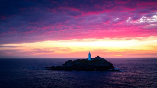 Stunning Lighthouse on a Rocky Island at Vibrant Sunset PC Wallpaper