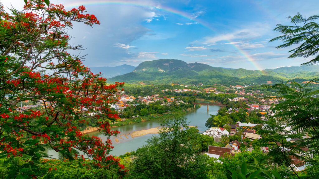 Breathtaking Luang Prabang Landscape with Rainbow and Red Flowers Desktop Wallpaper