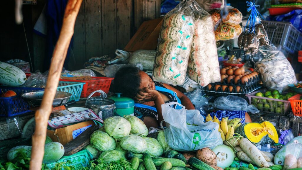 Tired Vendor Resting at Traditional Asian Market Desktop Wallpaper