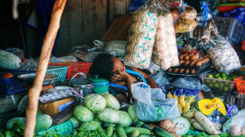 Tired Vendor Resting at Traditional Asian Market Desktop Wallpaper