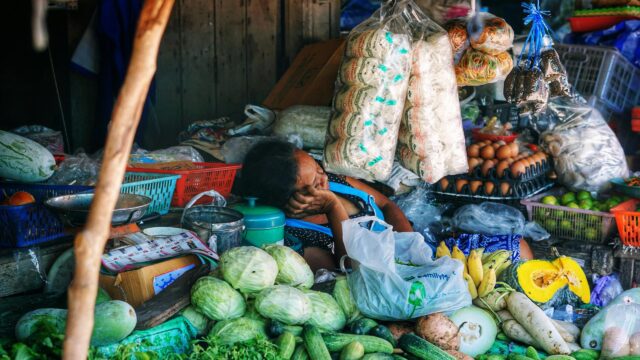 Tired Vendor Resting at Traditional Asian Market Desktop Wallpaper