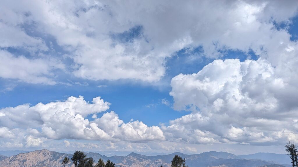 Breathtaking Mountain Range Under Fluffy White Clouds Desktop Wallpaper