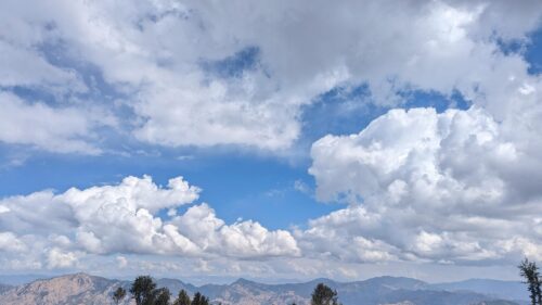 Breathtaking Mountain Range Under Fluffy White Clouds Desktop Wallpaper