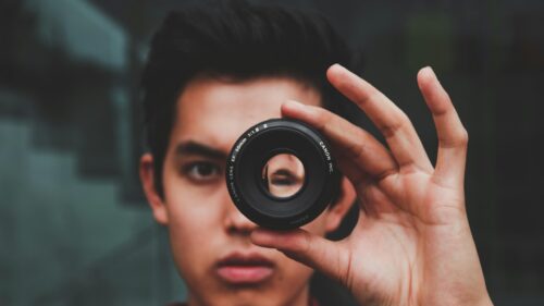 Young Man Holding Camera Lens Portrait 4K Desktop Wallpaper