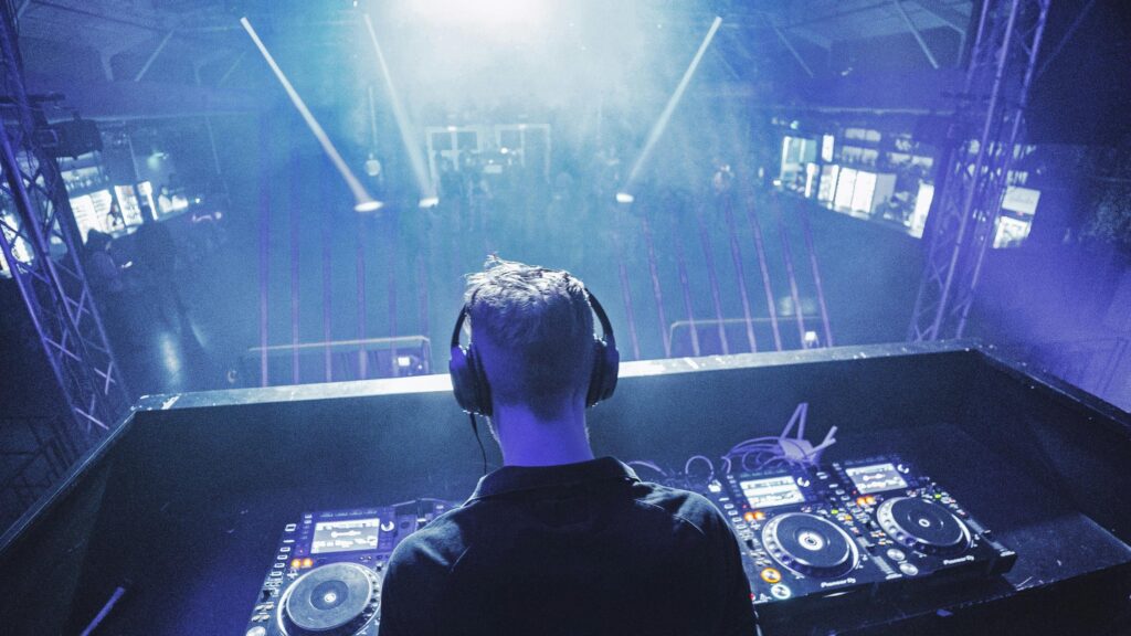 DJ Performing Live in Front of a Crowded Nightclub Stage Desktop Wallpaper