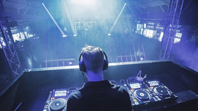 DJ Performing Live in Front of a Crowded Nightclub Stage Desktop Wallpaper