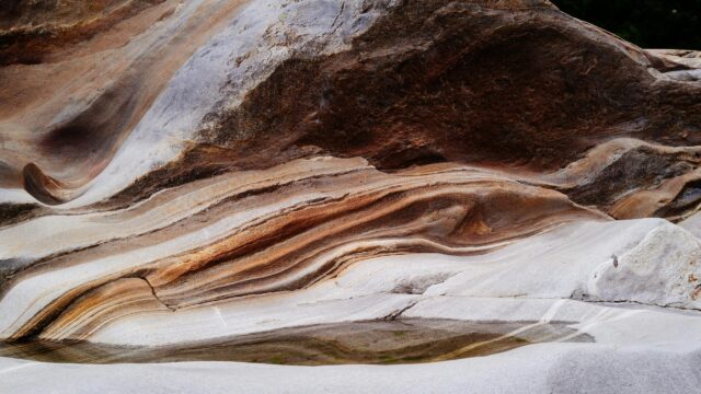 Stunning Layered Sedimentary Rock Formations with Natural Pool 4K Wallpaper