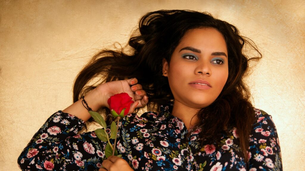 Beautiful Woman Holding Red Rose against Golden Backdrop 4K Wallpaper