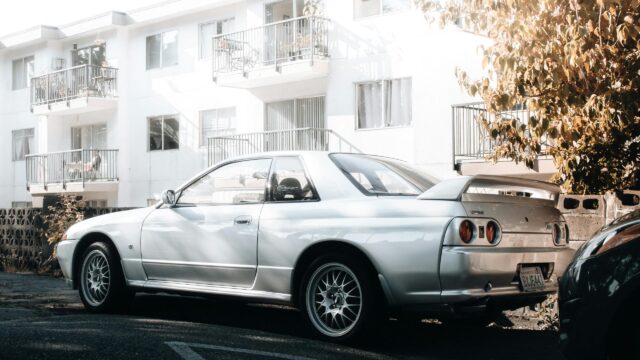 Silver Nissan Skyline R32 GT-R Parked by Apartment Building Desktop Wallpaper