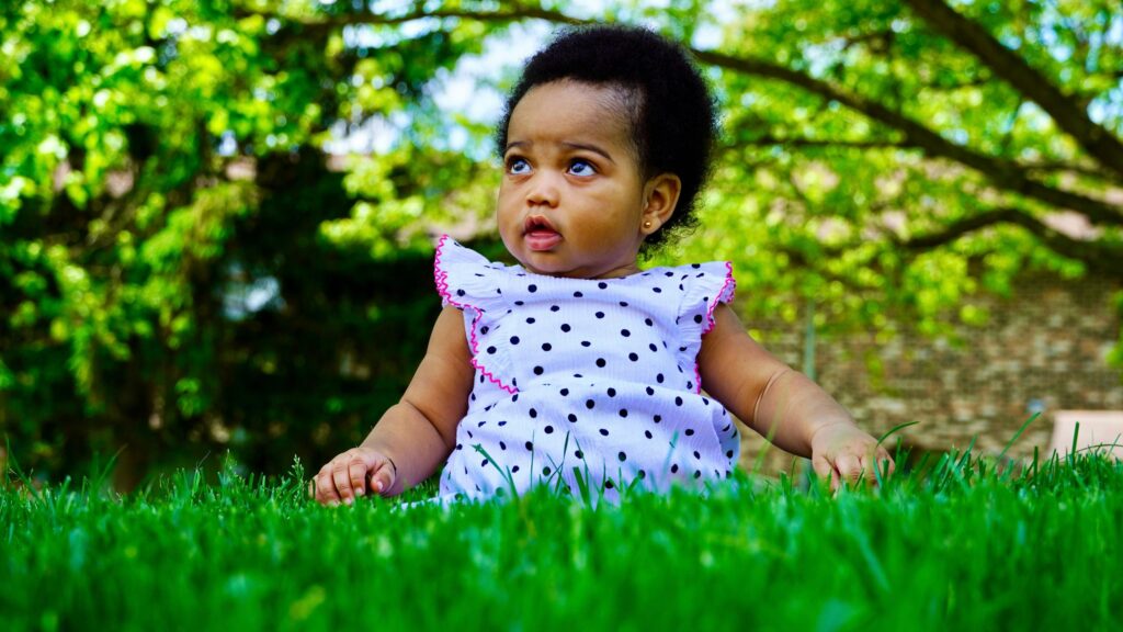 Adorable Baby Girl Sitting in Lush Green Grass Desktop Wallpaper