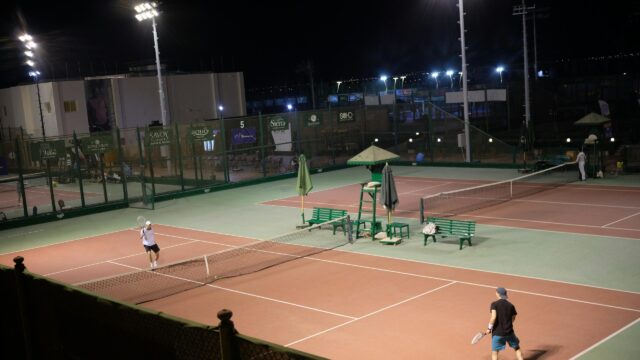 Tennis Players on Illuminated Outdoor Court at Night Desktop Wallpaper
