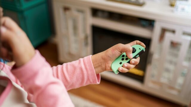 Casual Gamer Holding Pastel Green Joy-Con Controller 4K Wallpaper