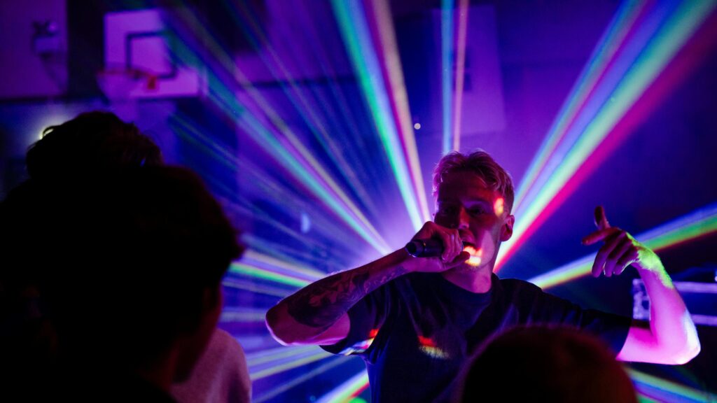 Energetic Hip Hop Performer in Vibrant Laser Concert Lights 4K Wallpaper