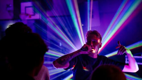 Energetic Hip Hop Performer in Vibrant Laser Concert Lights 4K Wallpaper