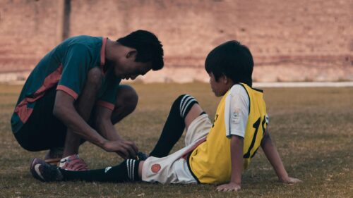 A Coach Helping a Young Soccer Player on the Pitch 4K Desktop Wallpaper