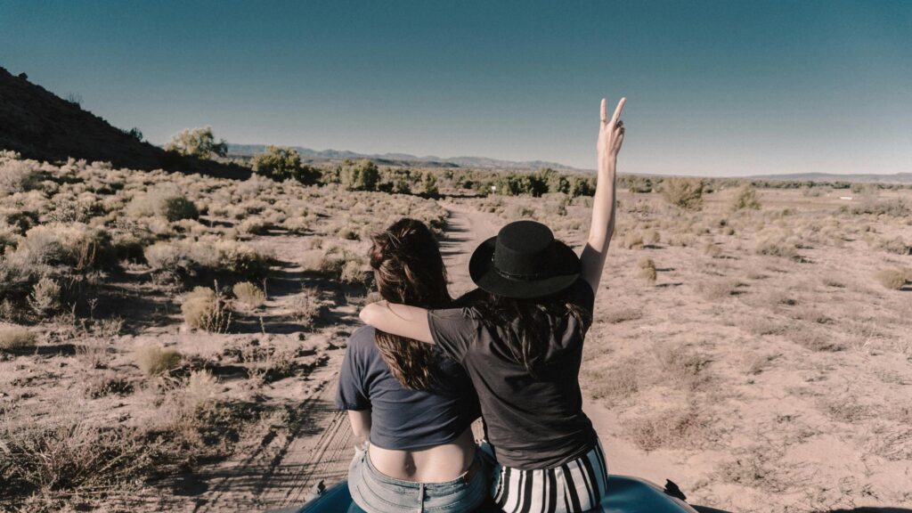 Two Women Enjoying Desert Road Trip Adventure Desktop Wallpaper