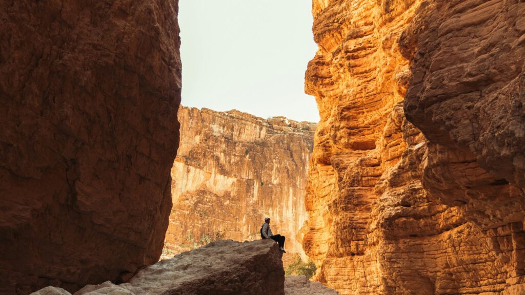 Lone Hiker Sitting on Canyon Rock 4K Wallpaper