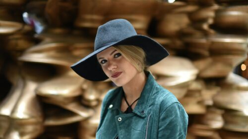 Elegant Blonde Woman in Dark Fedora Hat and Green Suede Jacket Desktop Wallpaper